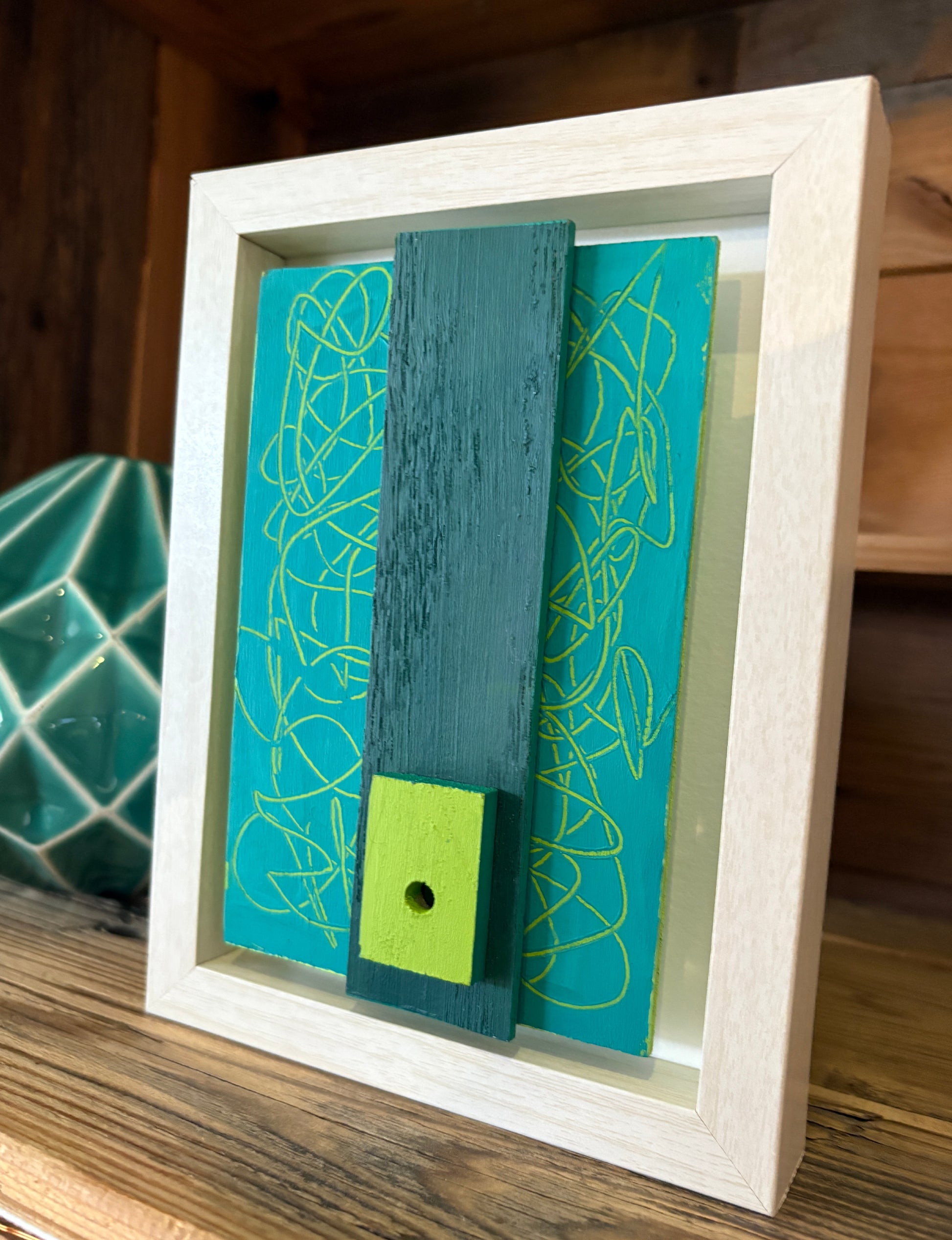 Mini Musings - Big Teal by Nancy Benoy. Framed abstract art piece with colorful geometric shapes on an orange background . Nancy Benoy is a featured artist for SOCIAL SPACE I Holiday Market at MRKT Box - Strathcona Market location from November 14 - 16,2025.