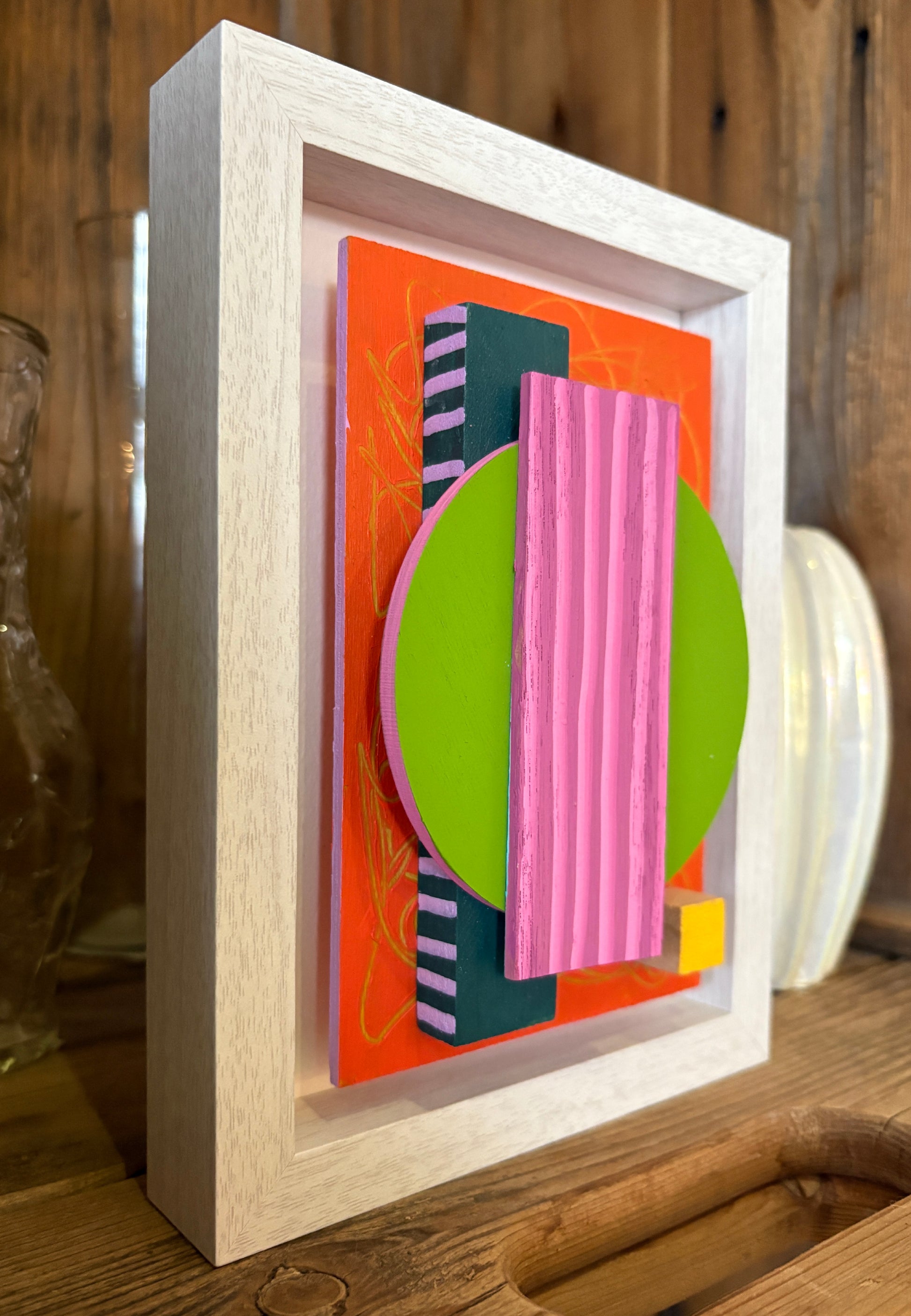Mini Musings - Pretty Hottie by Nancy Benoy. Framed abstract art piece with colorful geometric shapes on an orange background . Nancy Benoy is a featured artist for SOCIAL SPACE I Holiday Market at MRKT Box - Strathcona Market location from November 14 - 16,2025.